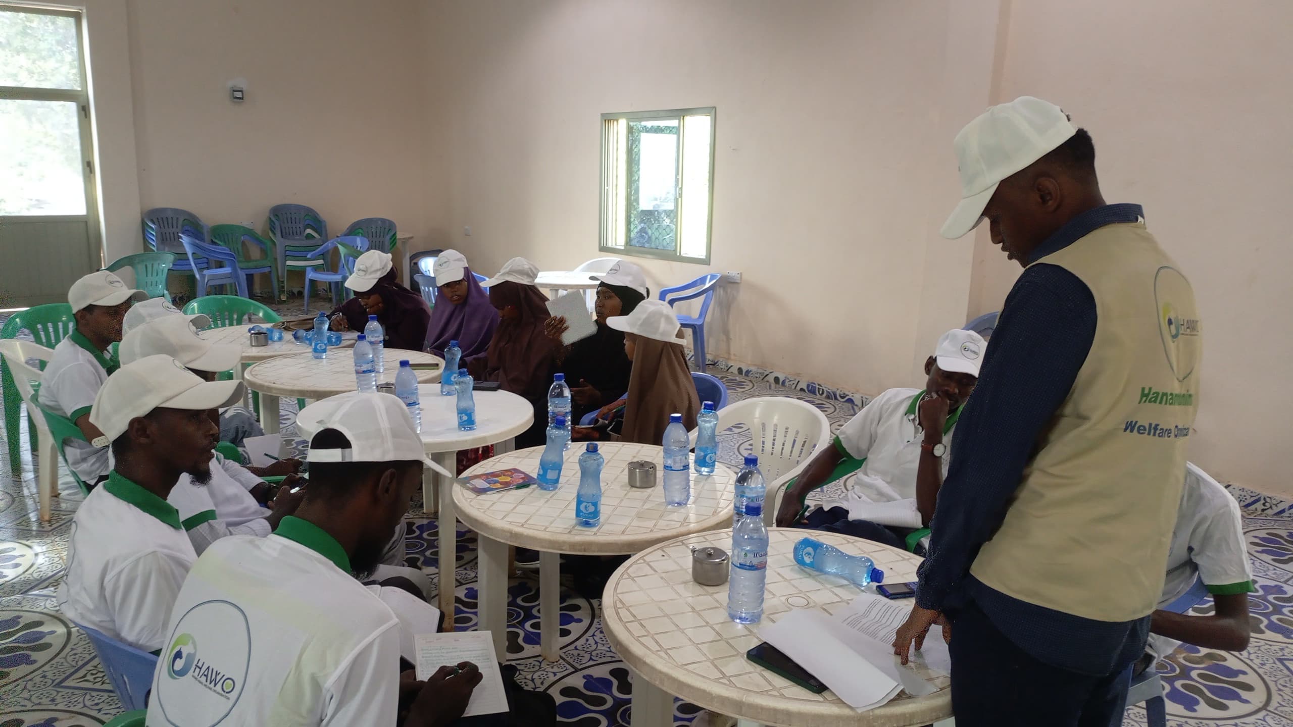 HAWO volunteers in white caps seated around tables during a training session in Kismayo